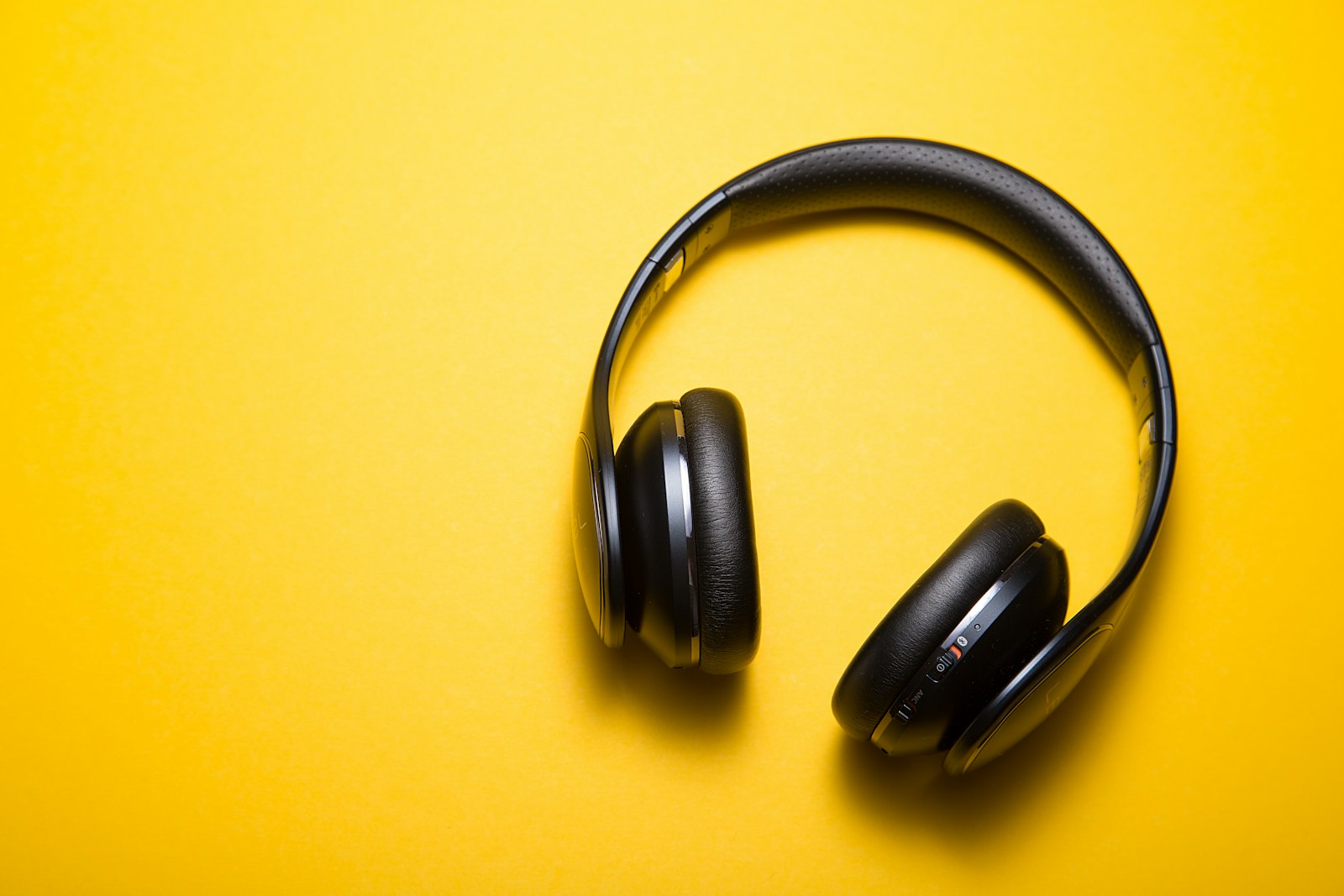 Black over-ear headphones with leather pads on a yellow background