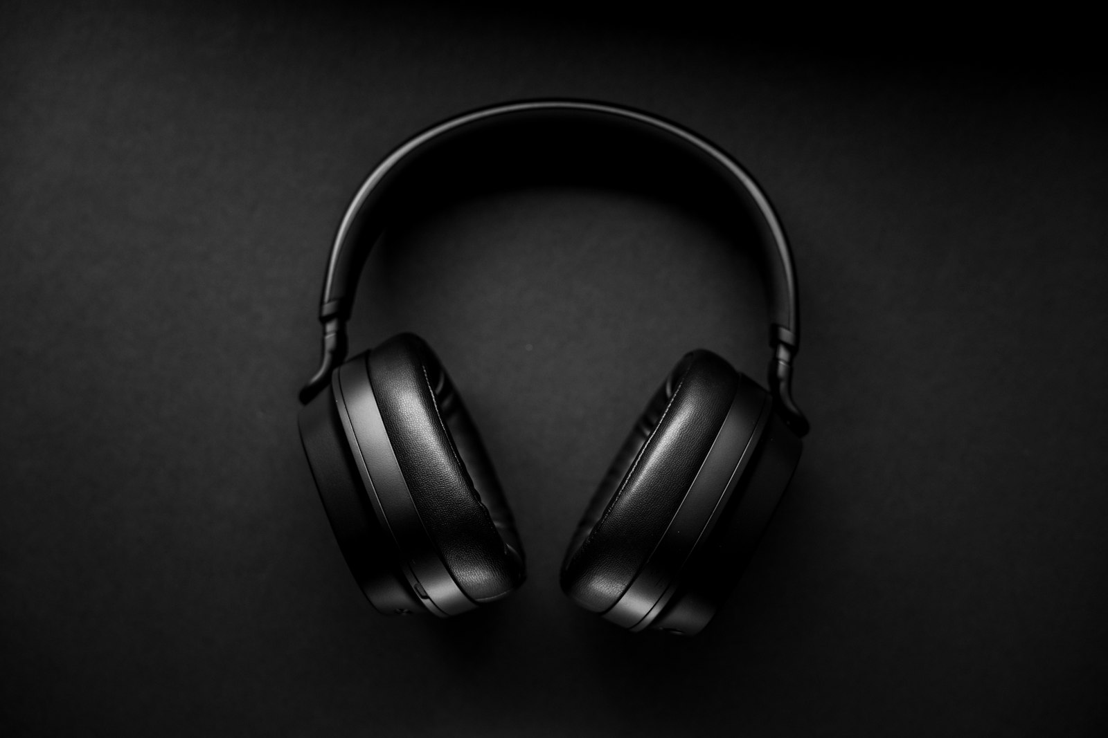 Black over-ear headphones seen from above on a dark surface